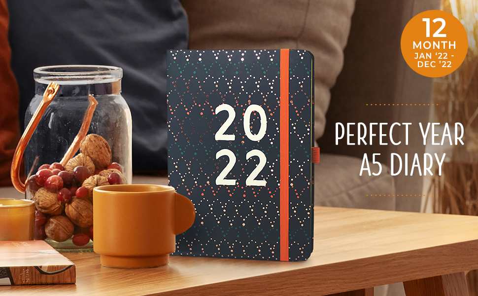 The 2022 Perfect Year A5 Diary stood on a coffee table next to a mug and a jar of potpourri.