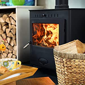 Close up of a stove with a log basket in front 