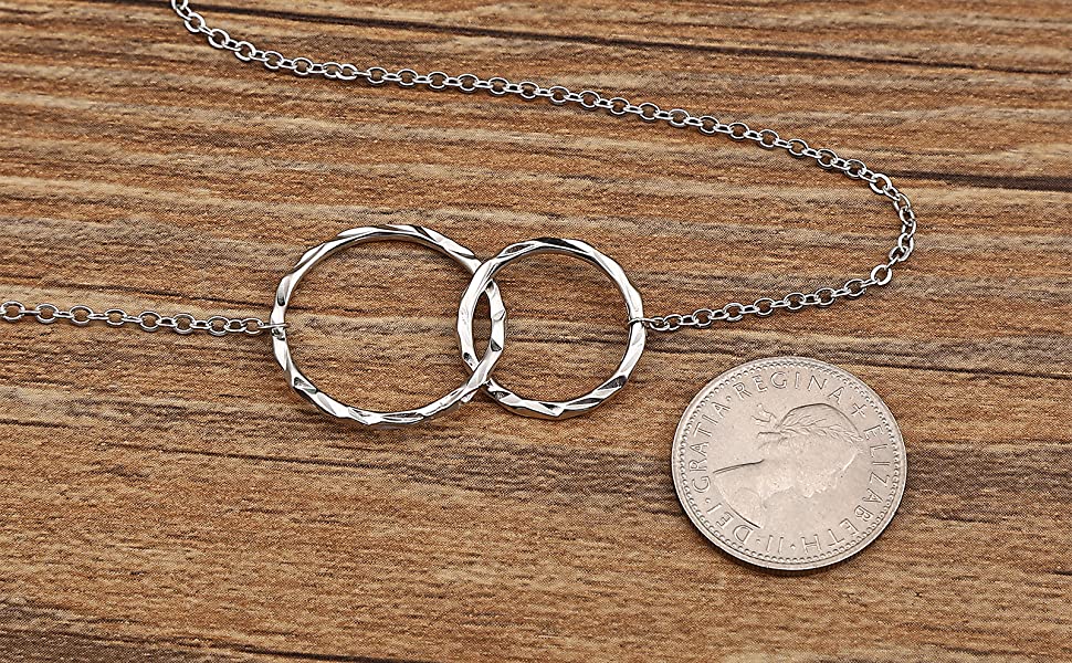 A comparison of the necklace with six pence coin on the woden table.