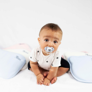 A Baby sitting among pillows for plagiocephaly with Koala Kiss pacifier from Koala Babycare