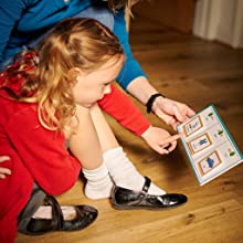 Parent and child looking at 3 picture cards helping the child get their shoes on. 