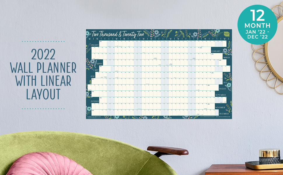 The 2022 Year Linear Wall Chart hung on a wall above a chair and desk with tray and ornament.