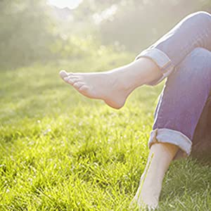 Person sitting in the grass with legs crossed and bare feet