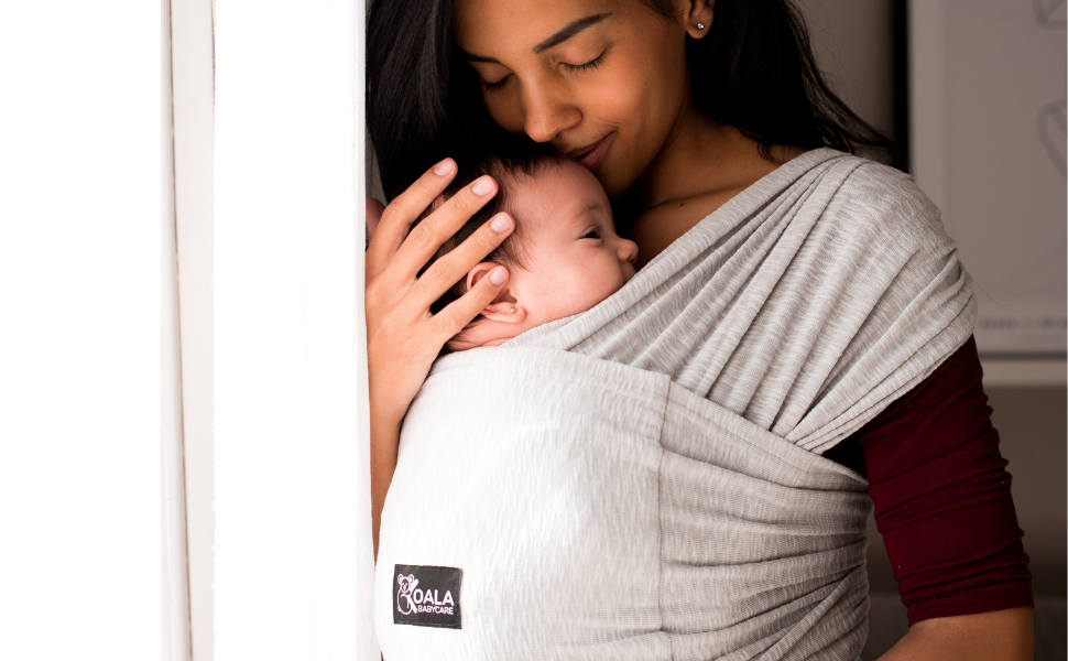 Mom kissing her daughter wearing the koala babycare baby wrap carrier in gray 